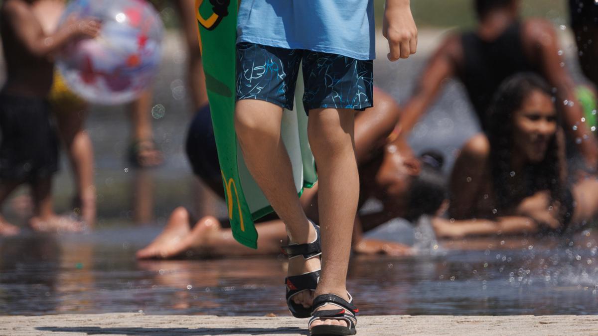 Varias personas juegan en el agua para refrescarse en Madrid Rio, a 26 de junio de 2023, en Madrid (España).