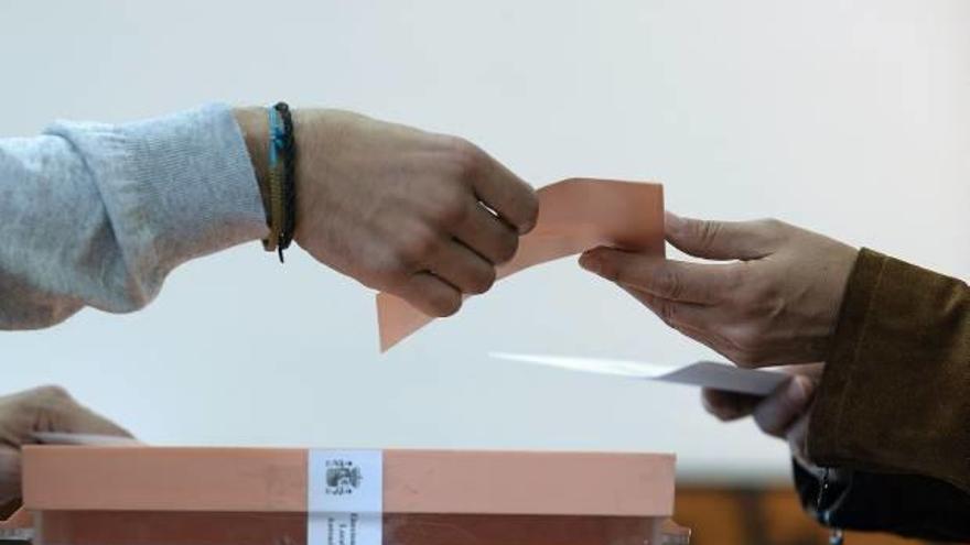 Un votante entrega su papeleta en unas elecciones autonómicas.