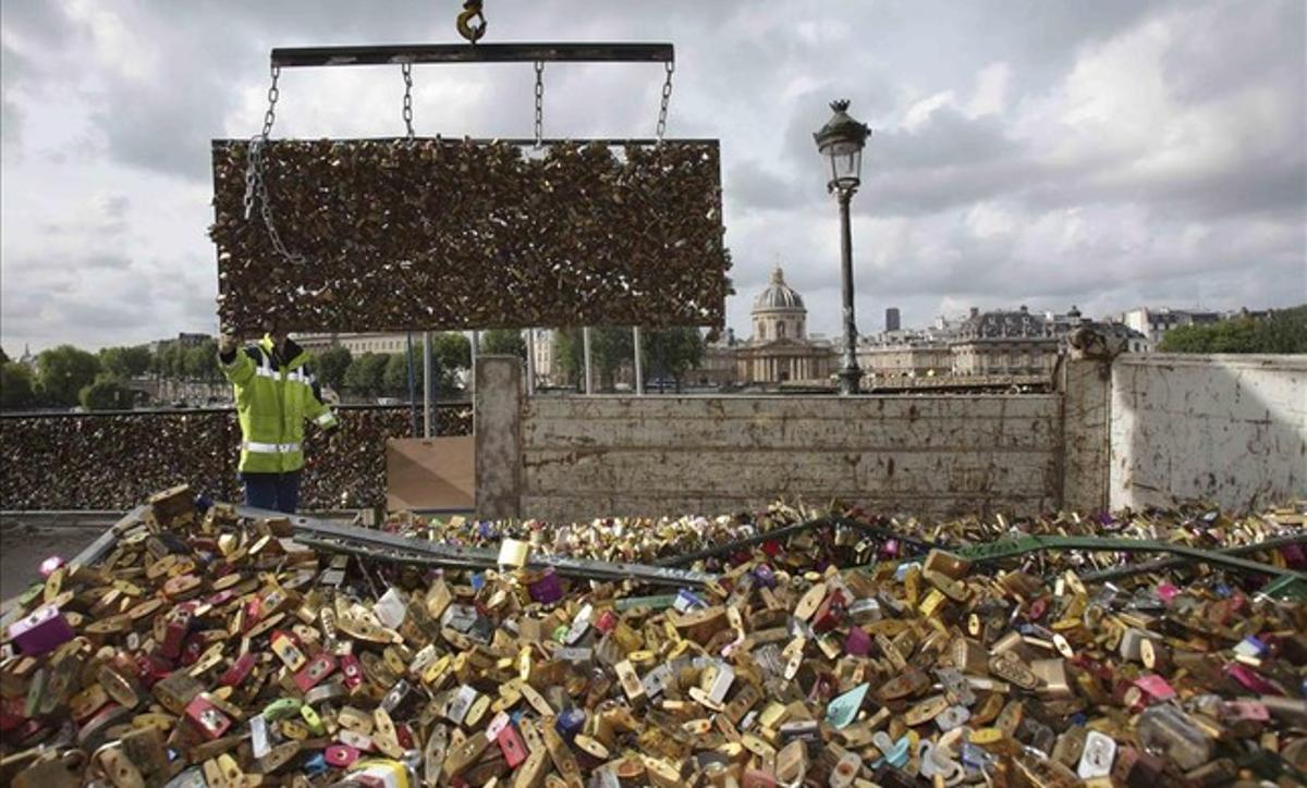 Uns operaris dipositen en un camió una de les baranes del pont de les Arts, a París, abarrotada de candaus.
