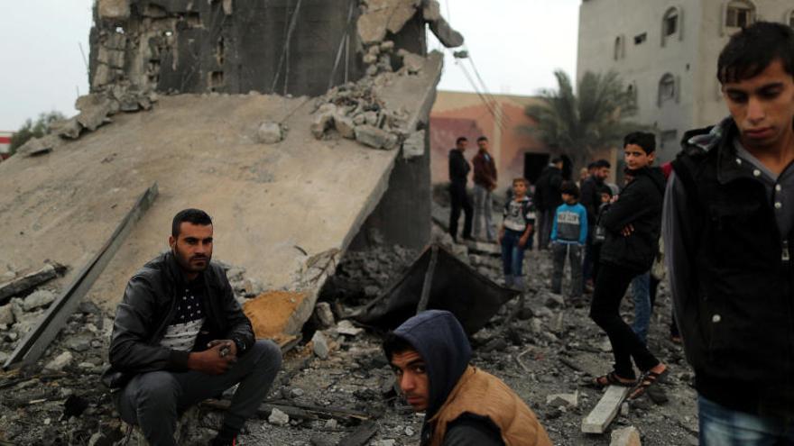 Palestinos ante un edificio destruido tras el ataque aéreo.