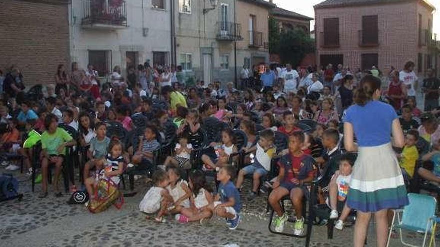 Niños y mayores disfrutan de una sesión de cine al aire libre.