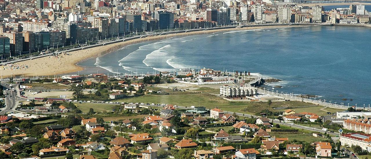 Vista del paseo marítimo gijonés, con los terrenos de la Ería del Piles a la izquierda en la zona central de la fotografía (frente a la playa y el hotel Abba). A la derecha de la imagen, el PERI 11, en la zona de Casablanca, terrenos con los que limita la APP 100, denominación en el PGO de la Ería del Piles.