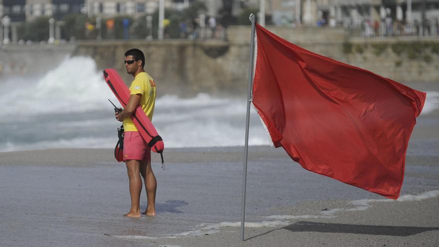 Un socorrista vigila una playa gallega con bandera roja. // C. Pardellas