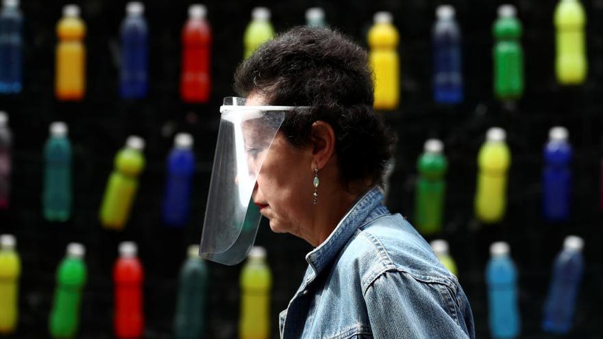 Una dona camina pel carrer a Madrid protegida per una pantalla protectora