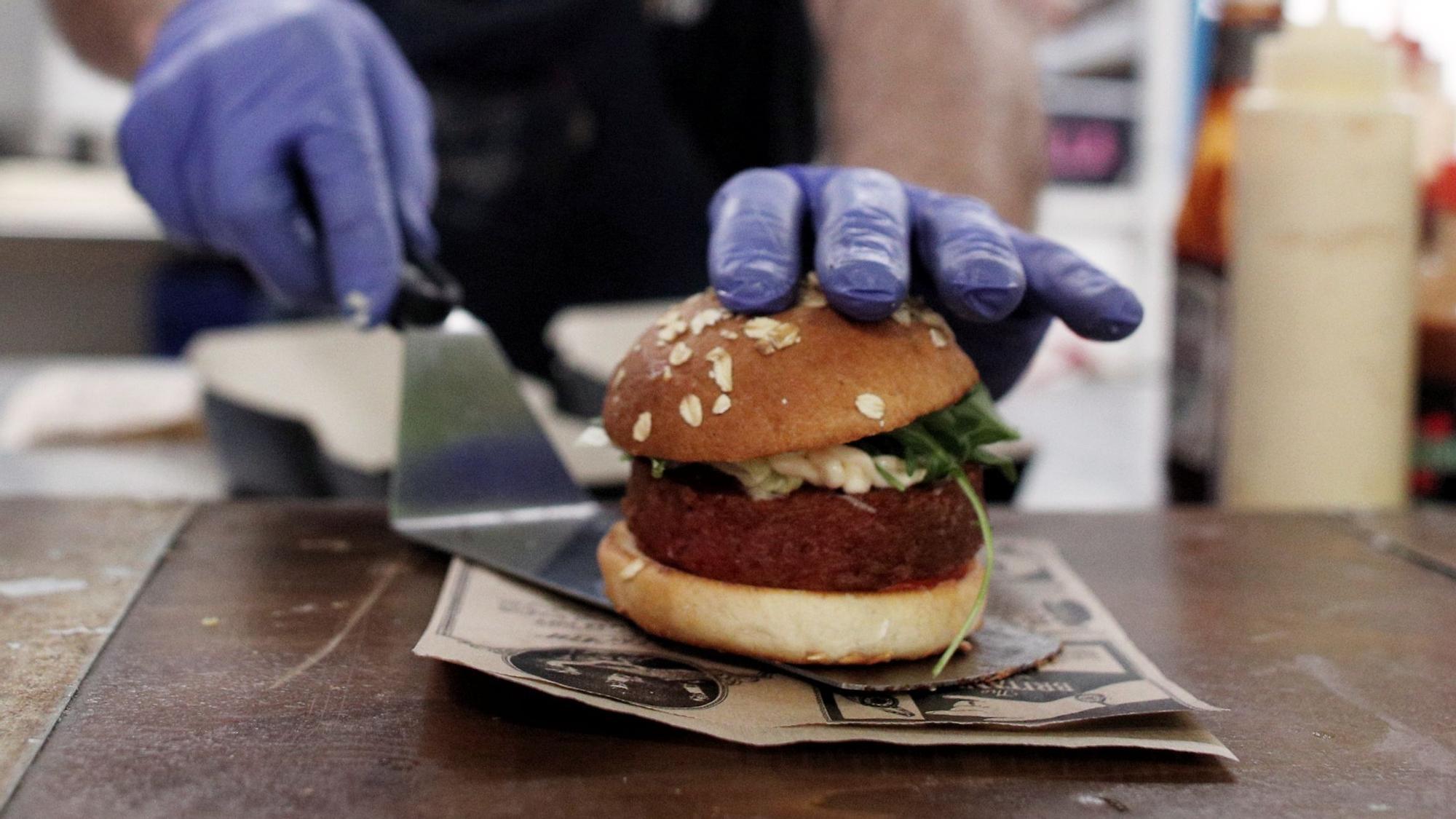 Un cocinero prepara una hamburguesa vegana.