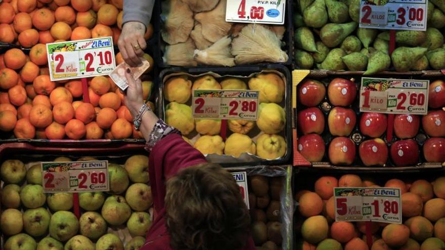 Una mujer paga la compra en una frutería.