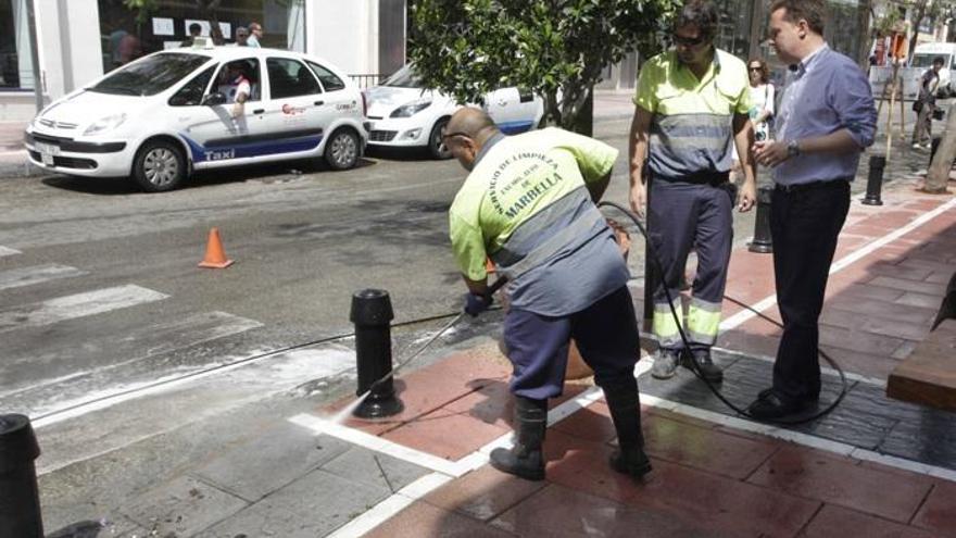 Operarios del servicio de limpieza de Marbella se afanan en retirar chicles pegados sobre la acera.