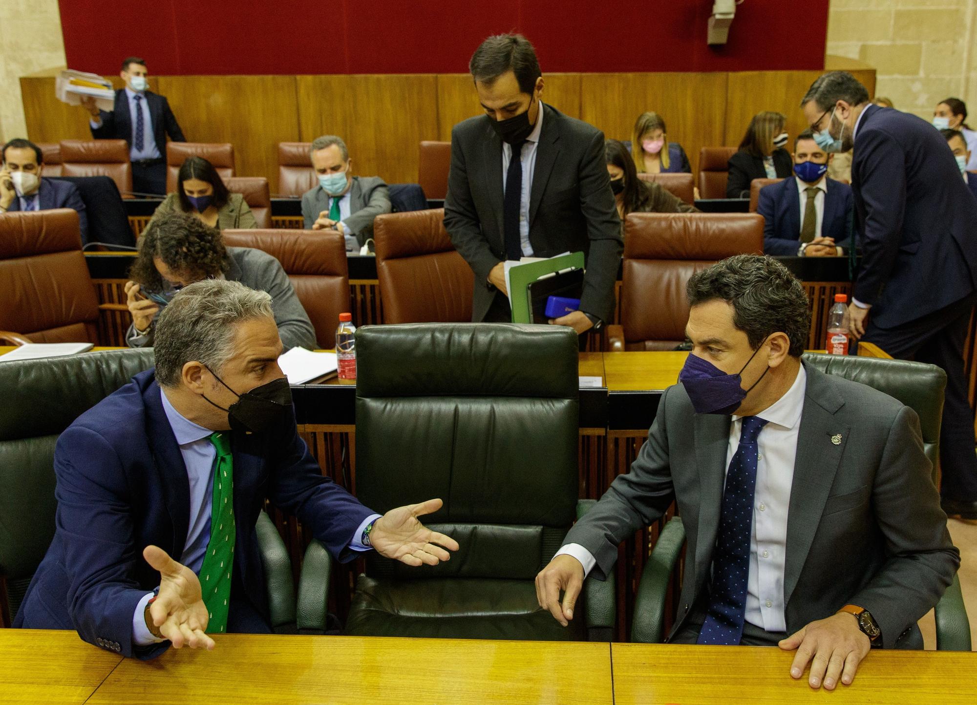 El presidente andaluz, Juanma Moreno, y el consejero de la Presidencia, Elías Bendodo, en sus escaños al comienzo del pleno del Parlamento de Andalucía el 9 de febrero de 2022.