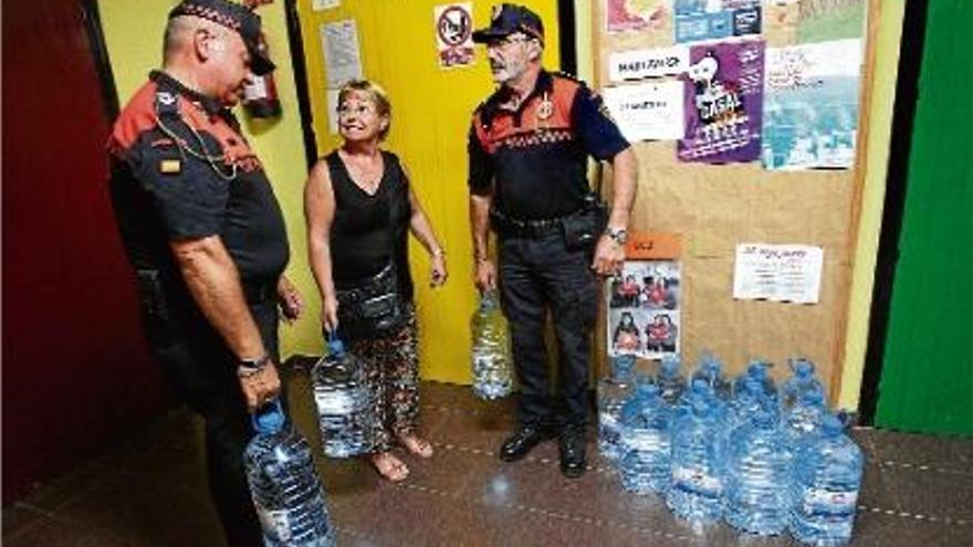 Efectius de Protecció Civil de la Bisbal entreguen garrafes d&#039;aigua a una veïna, ahir, a les Escoles Velles.