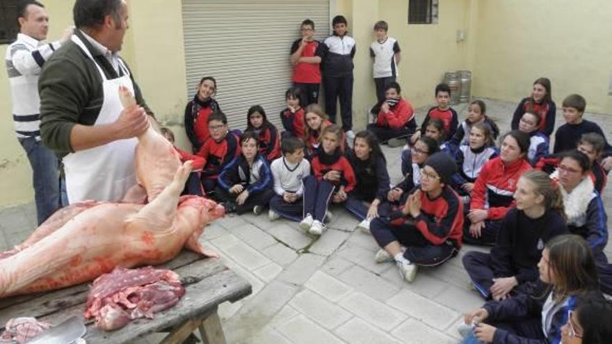 Los escolares escuchan las explicaciones de un carnicero en la Masía de la Cardadora.