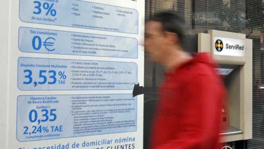 Un hombre pasa ante un cartel de anuncio de productos bancarios.