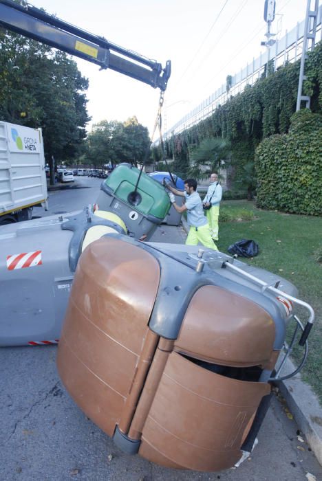 Carrers amb restes de mobiliari urbà cremat, contenidors per terra i treballadors de la brigada treballant