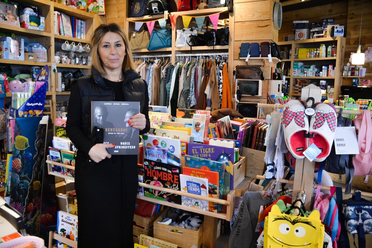 Raquel Pire sostiene uno de los últimos libros llegados a la sección de librería de su tienda, en Muros.
