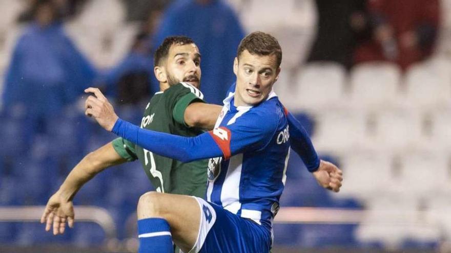 El delantero Oriol Riera, junto al bético Montoya anoche en Riazor.