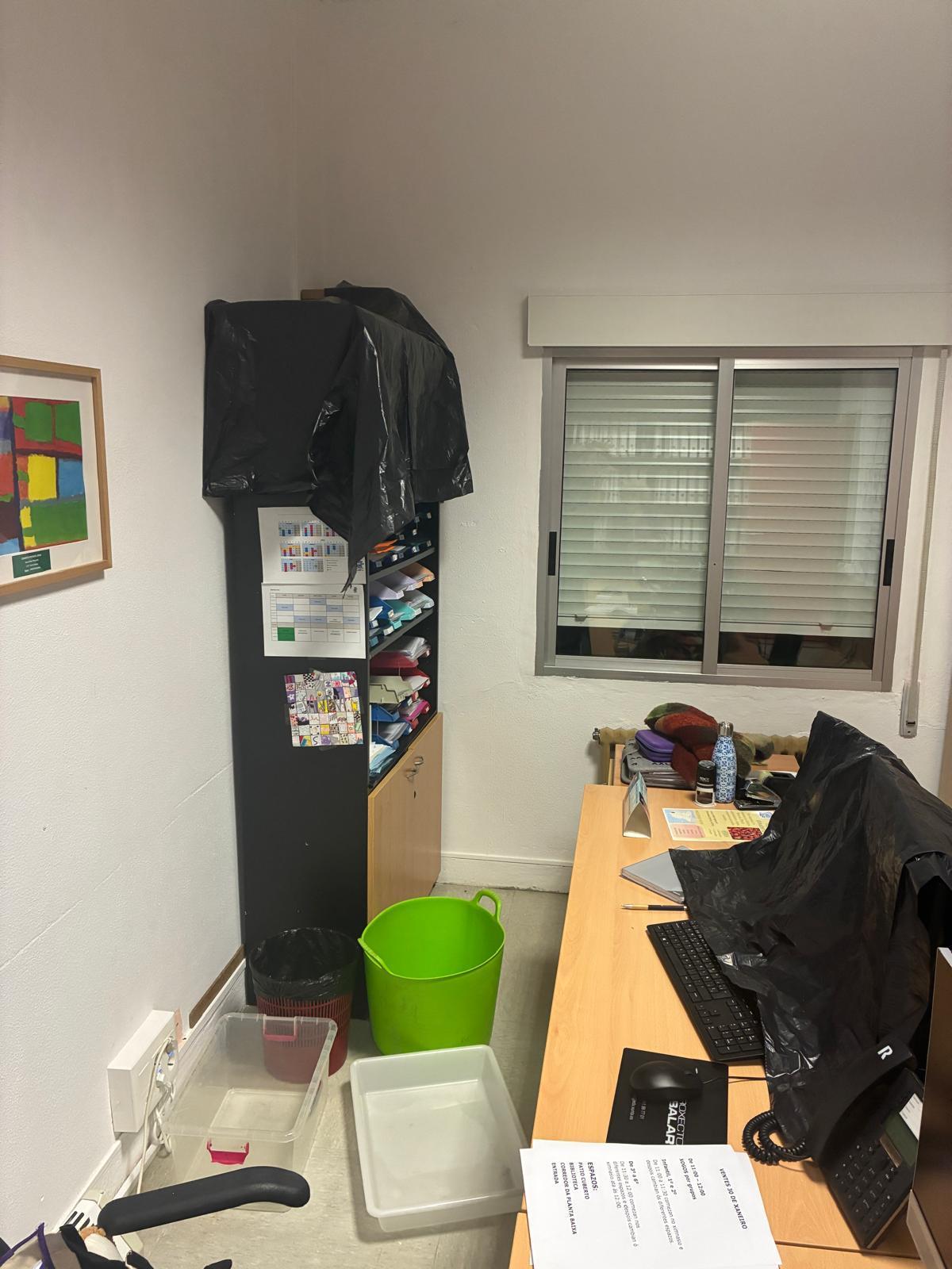 El despacho de dirección del colegio de Cela, con plásticos y cubos para evitar daños por las goteras.