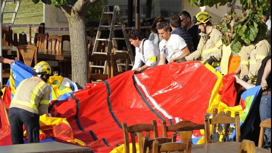 Operarios y bomberos retiran el castillo hinchable que salió volando el pasado domingo en Girona.
