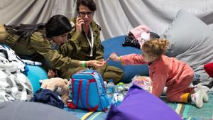 Esta fotografía publicada por la Oficina de Prensa del Gobierno de Israel (GPO) muestra a soldados jugando con Yahel Neri, la hija del ex rehén, el alemán israelí de doble nacionalidad Adi Shoham, después de que la madre (no en la imagen) y su hija fueran liberadas en medio de una operación de intercambio de rehenes. contra prisioneros entre Hamás e Israel, el 26 de noviembre de 2023.