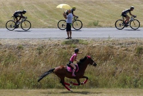 A girl rides a horse as the break away group of riders passes during the 17th stage of theTour de France cycling race