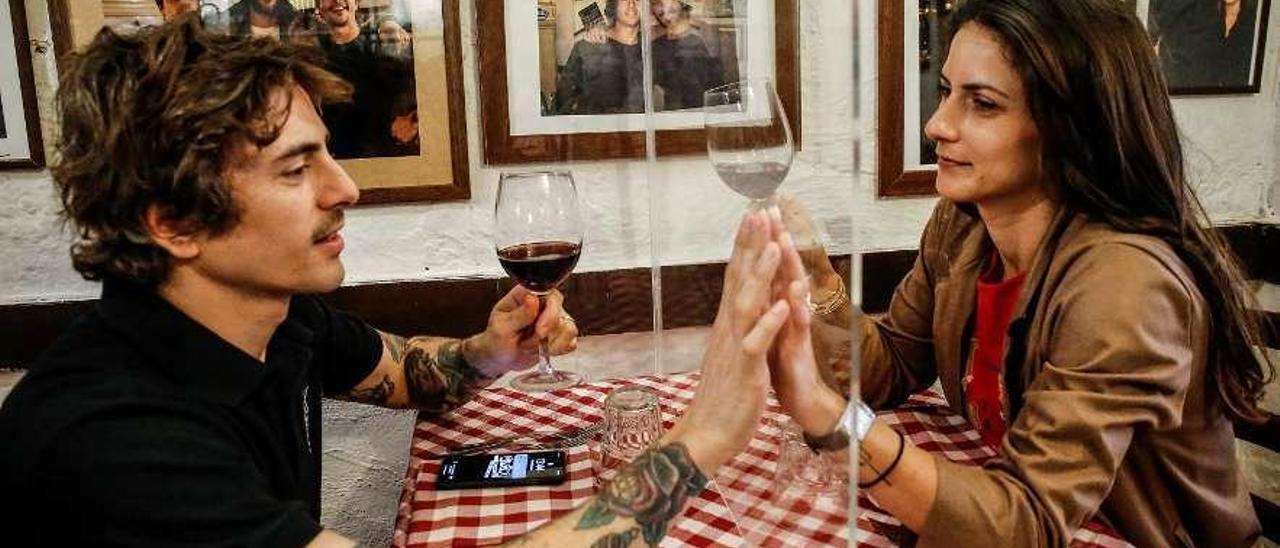 Mateo Calderoni, propietario de un restaurante en Roma, prueba con su mujer, Martina, una pantalla de metacrilato instalada para dividir las mesas del local.