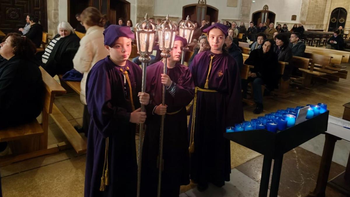 Tres niños de la cofradía con faroles, anoche, en la iglesia de Villaviciosa, tras confirmarse la suspensión de la procesión del Silencio. | A. G.-O.