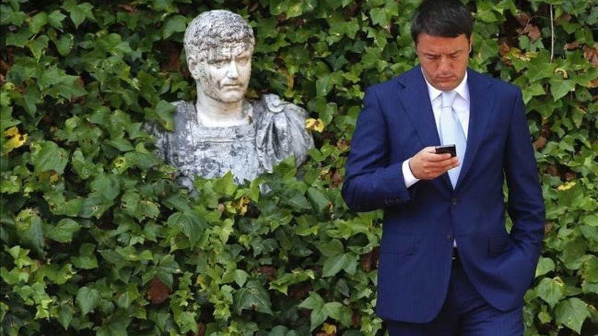 Matteo Renzi mira al móvil mientras espera la llegada del presidente de la Comisión Europea, en verano del 2014, en Roma.