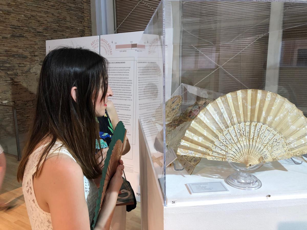 Una asistente a la inauguración admira un abanico.