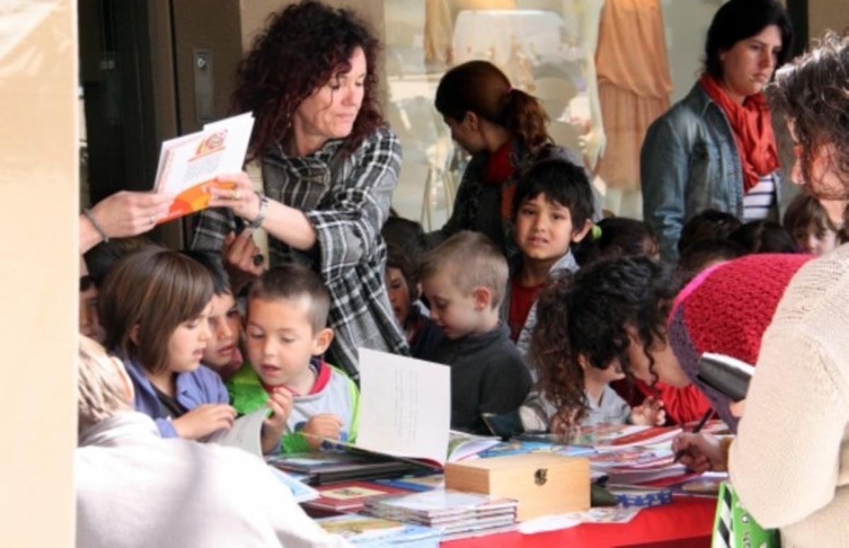 Uns nens miren els llibres d’una parada, a Vic.