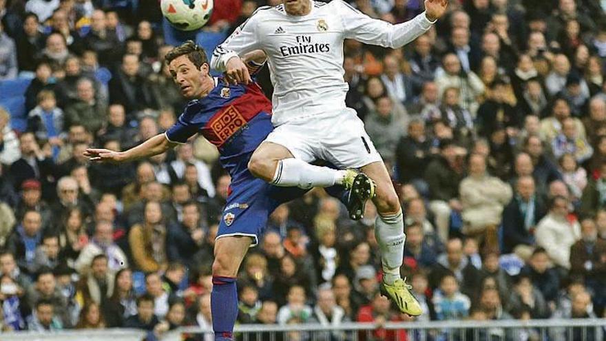 El jugador del Elche Edu Albacar, a la izquierda, disputa un balón con Bale.