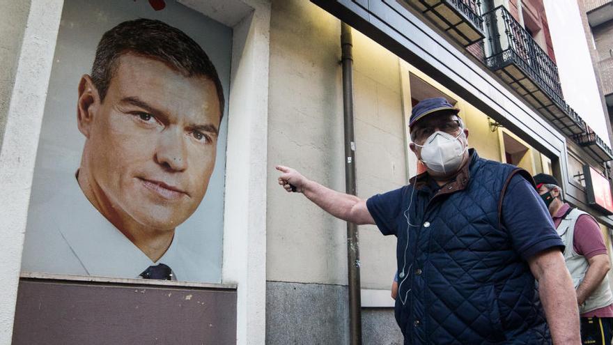 Un home senyala un cartell amb la foto de Pedro Sánchez durant una protesta a Madrid