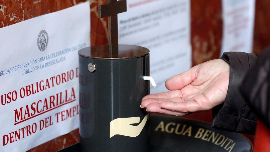 Una persona prueba el dispensador de agua bendita.