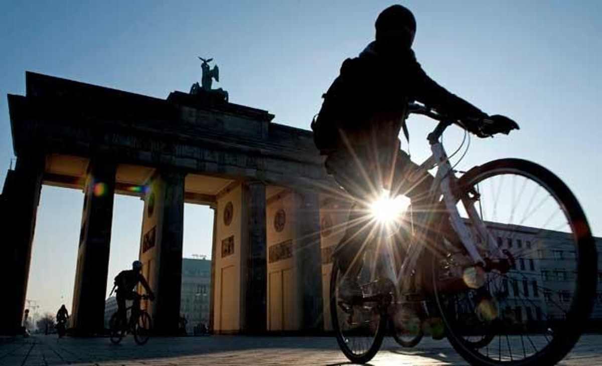 Uns ciclistes passen per la porta de Brandenburg al fer-se de dia a Berlín, Alemanya.