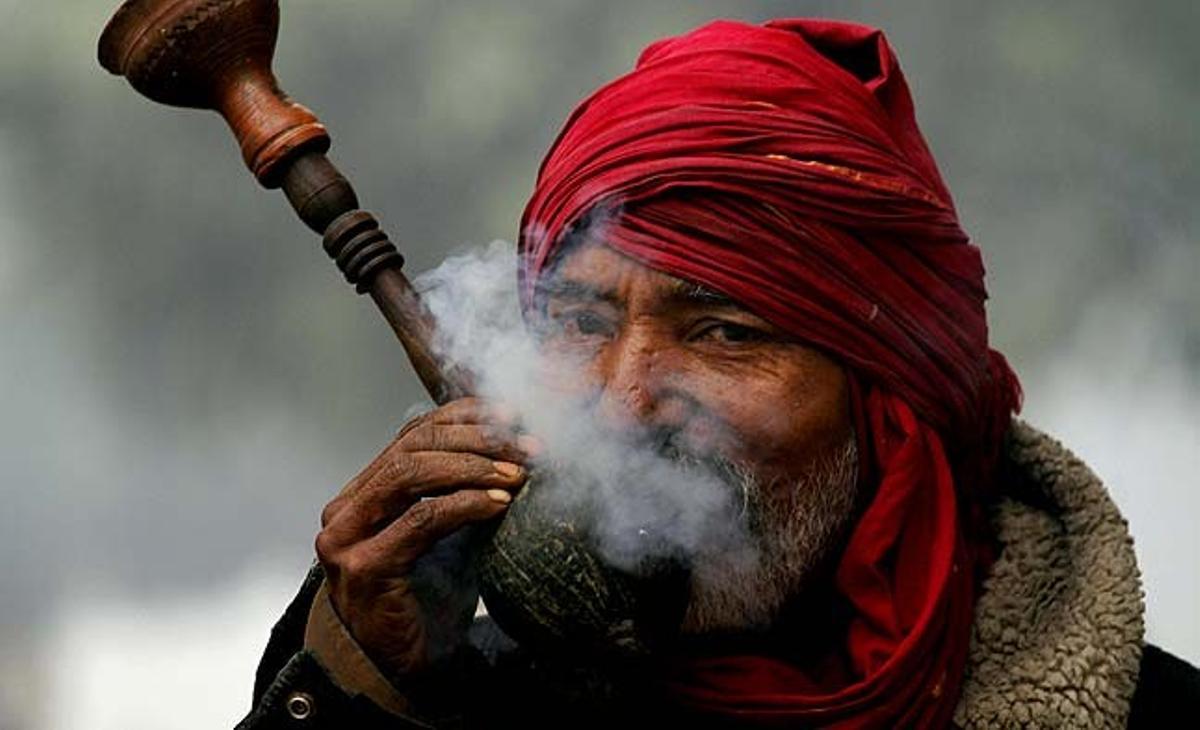 Un home fuma marihuana en un matí fred i amb boira a Allahabad (Índia).
