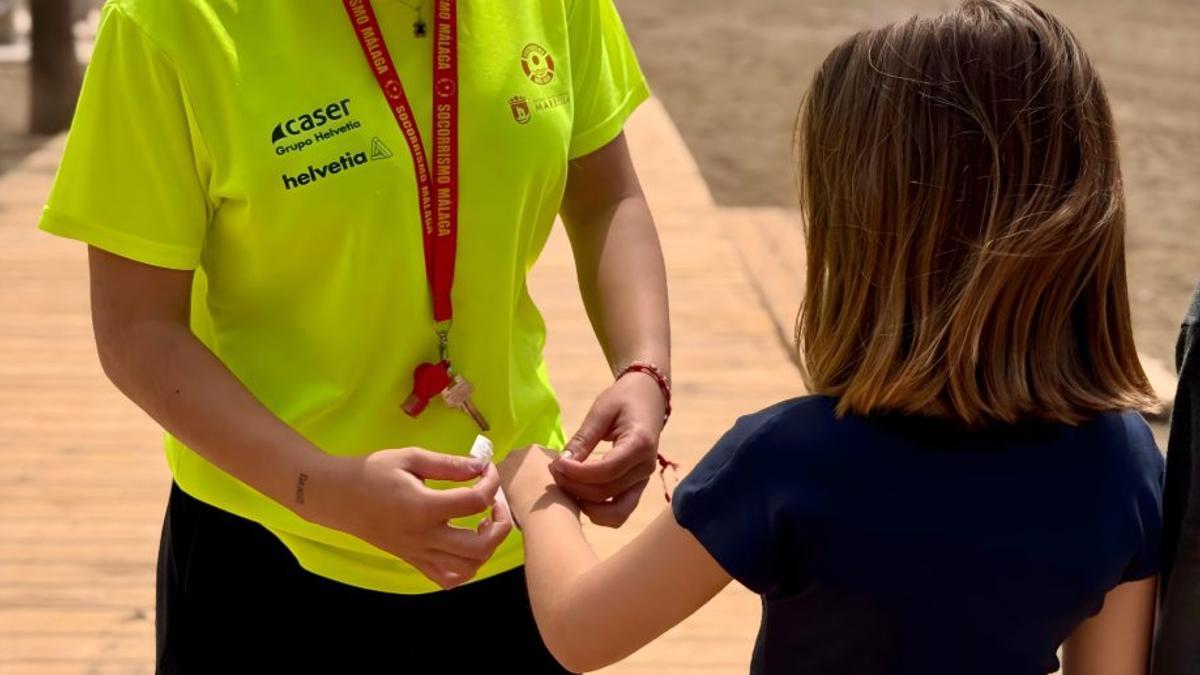 Una socorrista pone una pulsera de seguridad a una menor. | L.O.