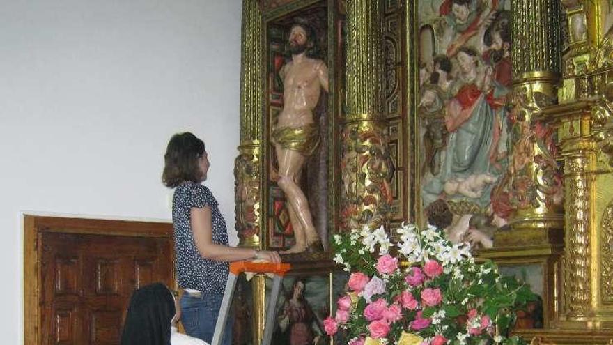 Una religiosa supervisa la colocación de la obra en el retablo.