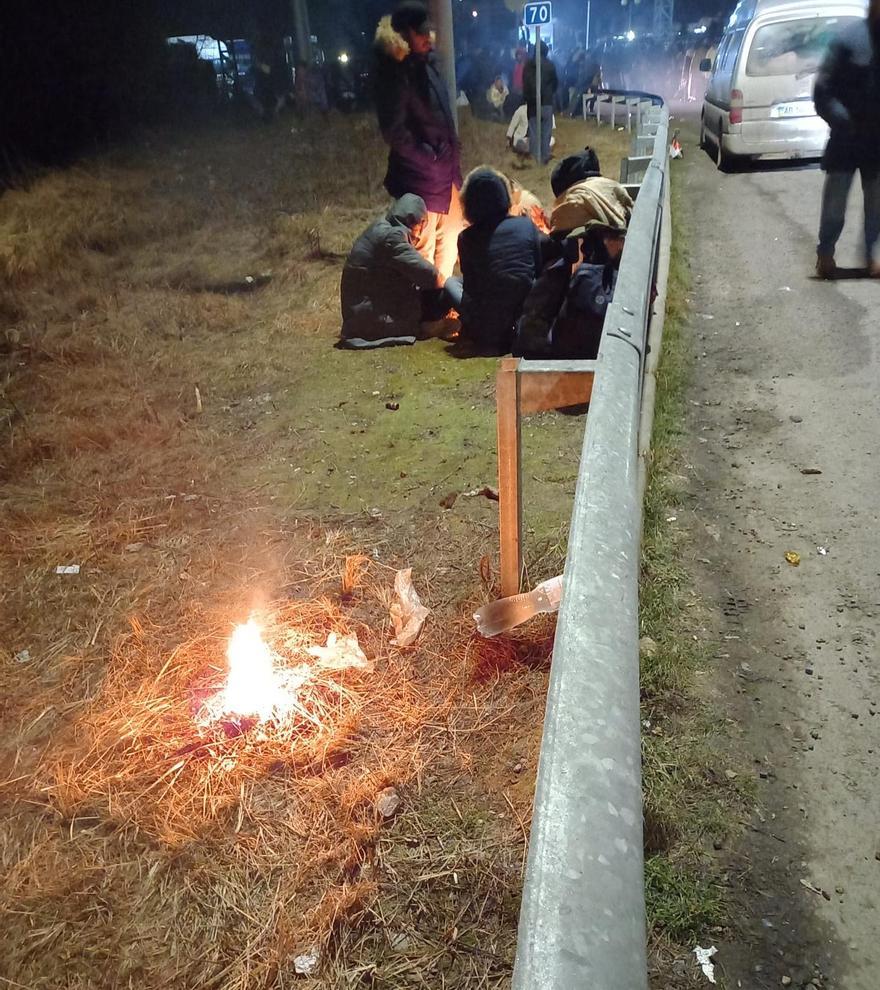 Ciudadadanos que huyen de Kiev se calientan junto al fuego en los márgenes de la carrretera