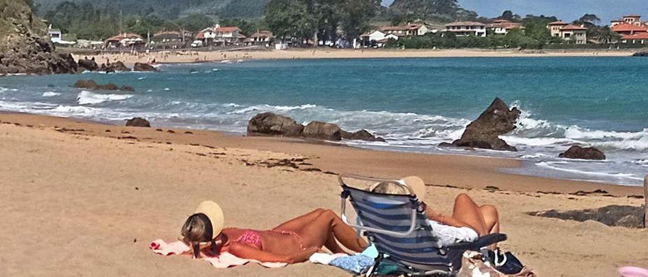 Dos bañistas toman el sol durante la mañana de ayer en El Barrigón; al fondo, La Isla.