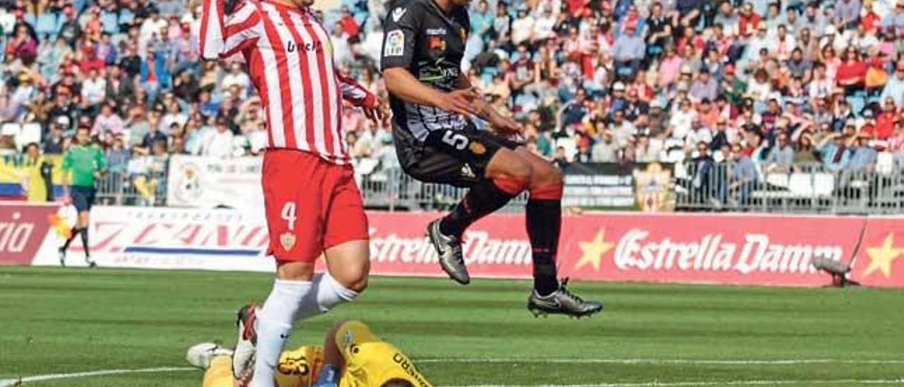 Cabrero atrapa un balón desde el suelo ante la llegada de Ximo, jugador del Almería.