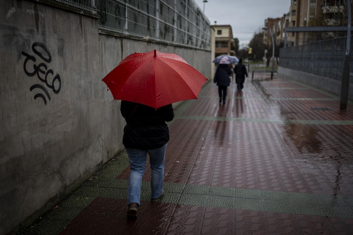 Una persona con un paraguas bajo la lluvia caminando por una calle de Zaragoza