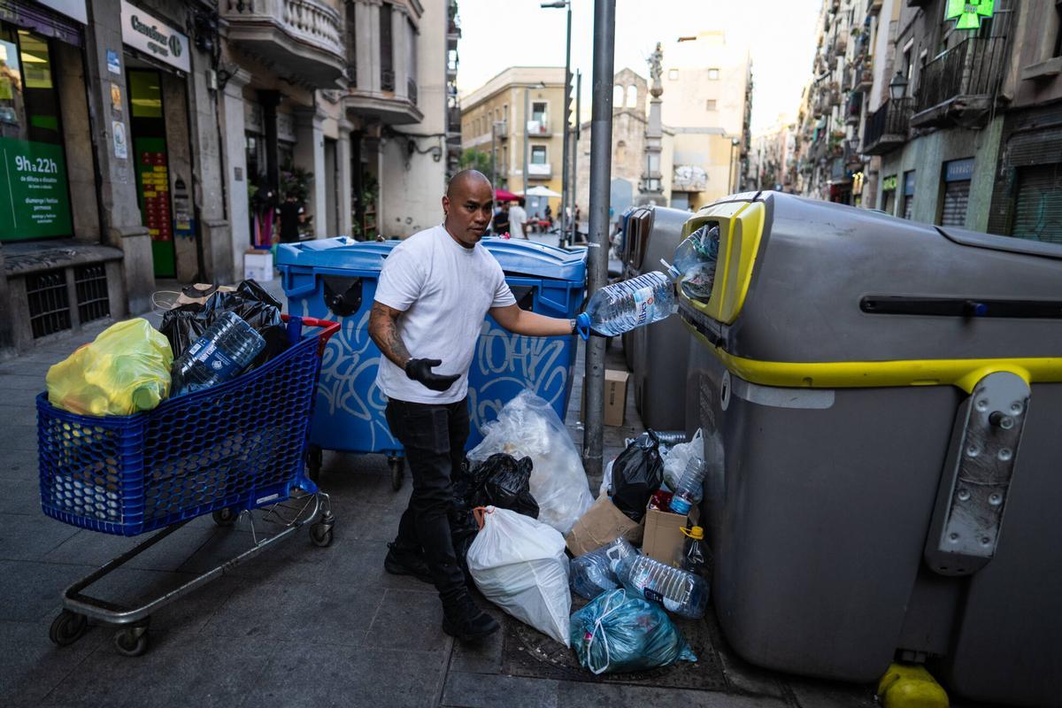 Barcelona. Jeffrey, propietario del bar Never, en la calle Cera 17 del barrio del Raval, retira con un carro de la compra las bolsas de basura acumuladas frente a su establecimiento antes de abrir el local, una situación que denuncia como habitual cada tarde. 29 de julio de 2026. Sociedad. AUTOR: ZOWY VOETEN