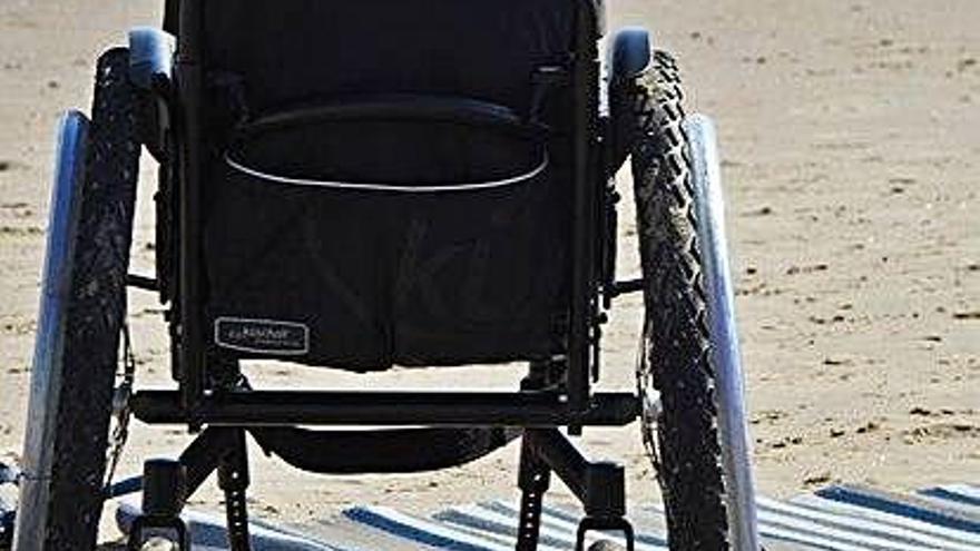 Una silla de ruedas en la arena de una playa.