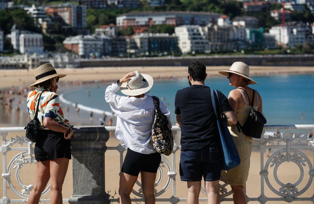 Unos turistas visitan la playa de la Concha de San Sebastián