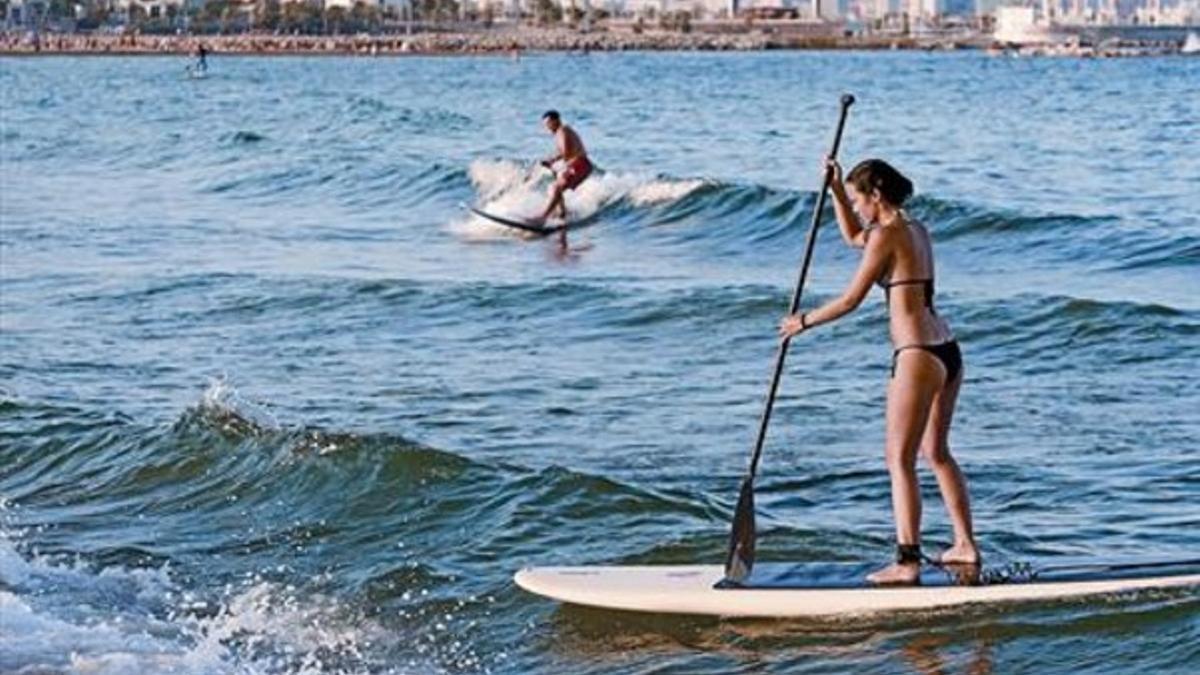 Un hombre y una mujer practican paddlesurf en aguas de la Barceloneta, el pasado 7 de agosto.