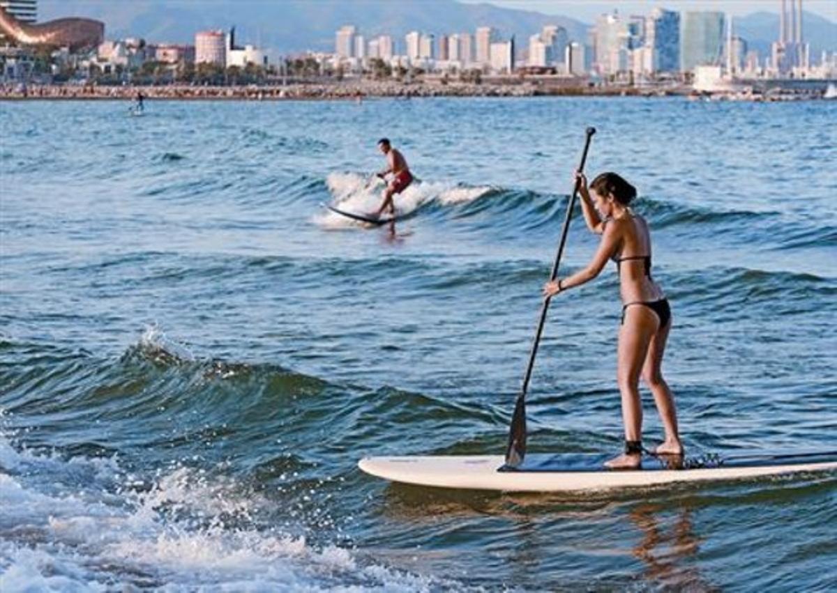 Un home i una dona practiquen paddlesurf en aigües de la Barceloneta, el 7 d’agost.