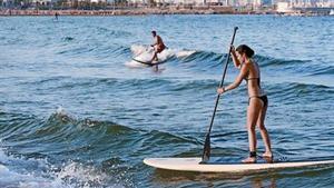 Un home i una dona practiquen paddlesurf en aigües de la Barceloneta, el 7 d’agost.