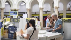 Varias personas en los mostradores de una oficina de Correos de Sevilla