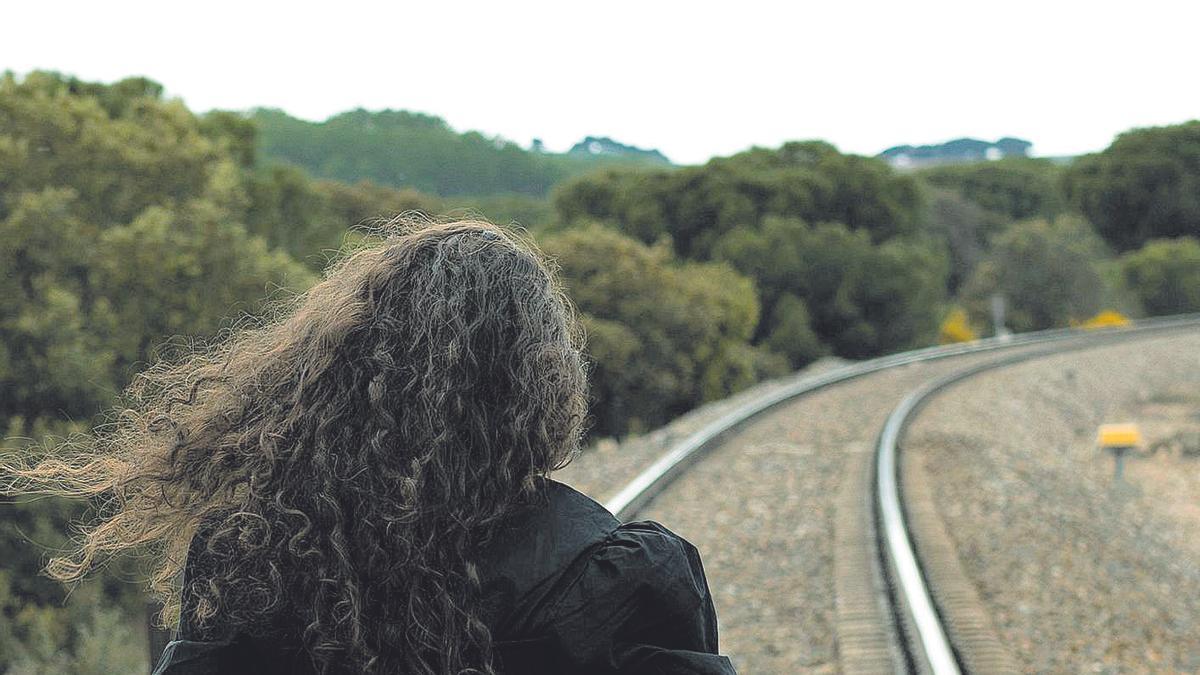 Una mujer caminando por una vía del tren.