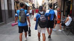 Tres jóvenes pasean por la calle del Mar de Badalona al volver de la playa.