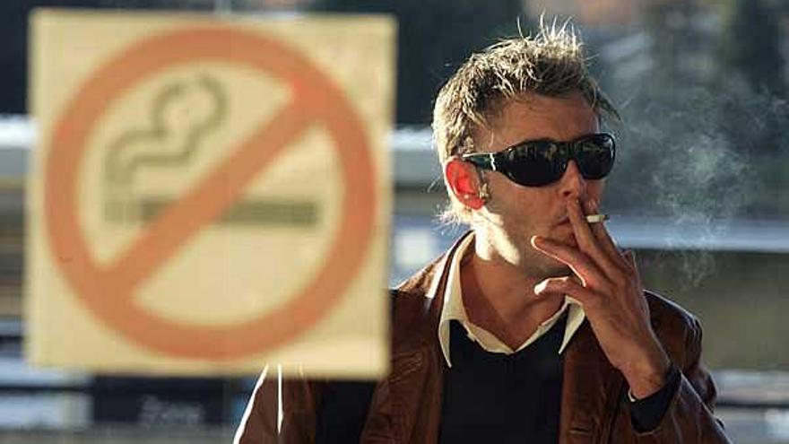 Un hombre, fumando en la calle.