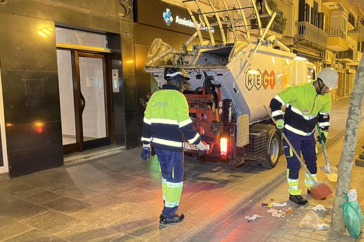 Un treballador escombra restes de brossa mentre recullen les escombraries de Blanes.