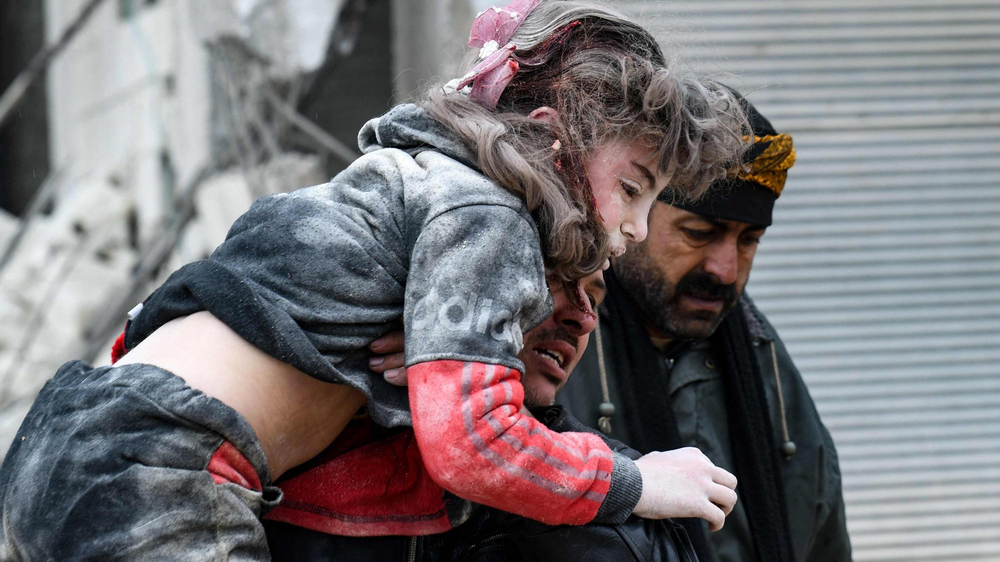 Los residentes cargan a un niño herido de los escombros de un edificio derrumbado tras un terremoto en la ciudad de Jandaris.